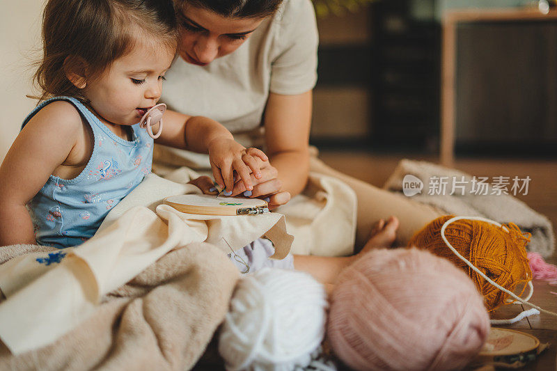 一个女人和她的女儿一起为家里做手工装饰的特写。女人把打孔针直接扎进布料里。爱好、DIY、手工概念