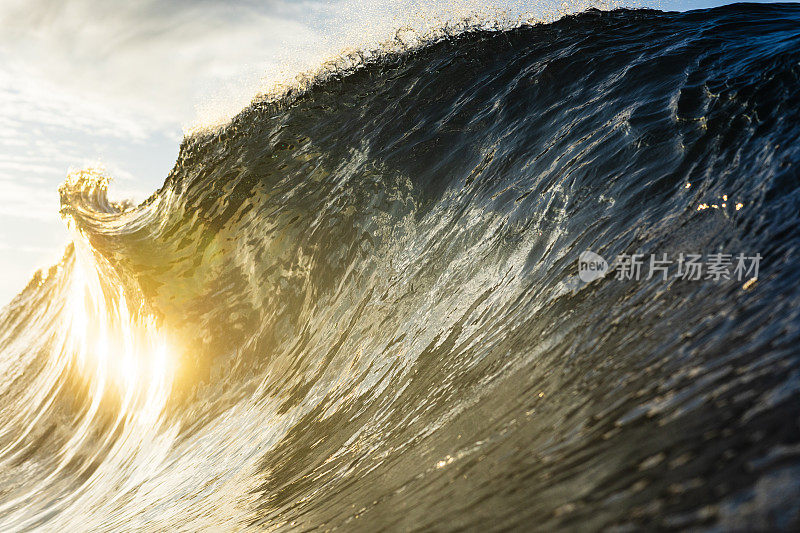 强大的背光海浪在明亮的金色晨光中破碎的特写