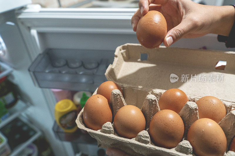 用手从鸡蛋纸盒中取出鸡蛋放入冰箱