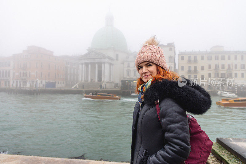 穿着保暖衣服的美女站在大运河边，游览意大利威尼斯