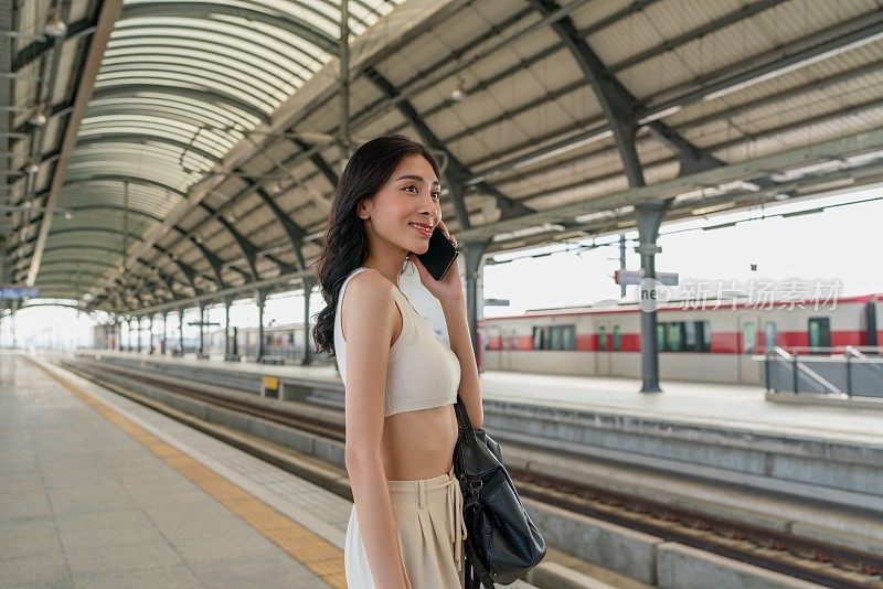 年轻的亚洲女子在地铁站台上打电话。无处不在的数字银行。商业在移动。年轻的亚洲女商人放松周末旅行。