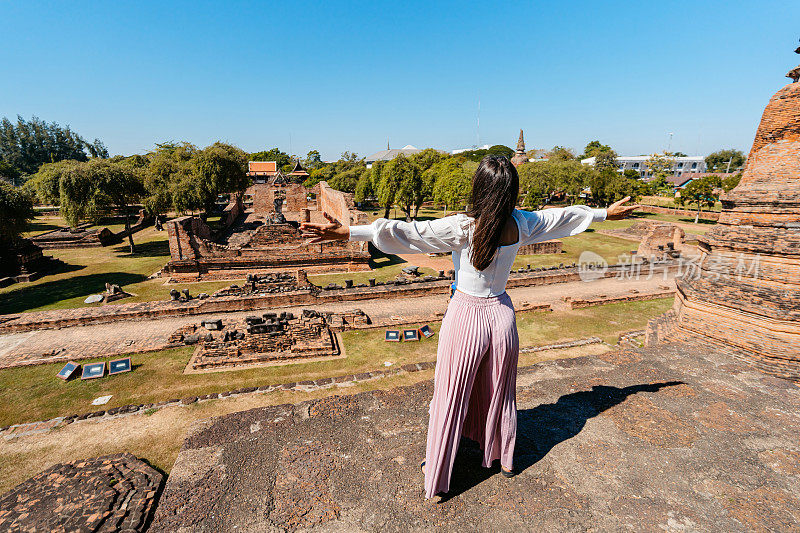 一位年轻女子在泰国大城府历史公园的Ratchaburana寺欣赏风景的后景