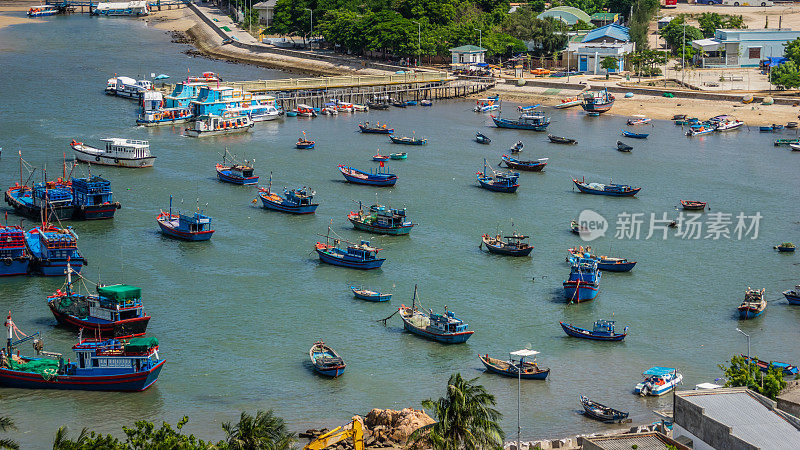 站在渔船和旅游船前，在越南宁顺清澈的蓝色海水下，紧挨着