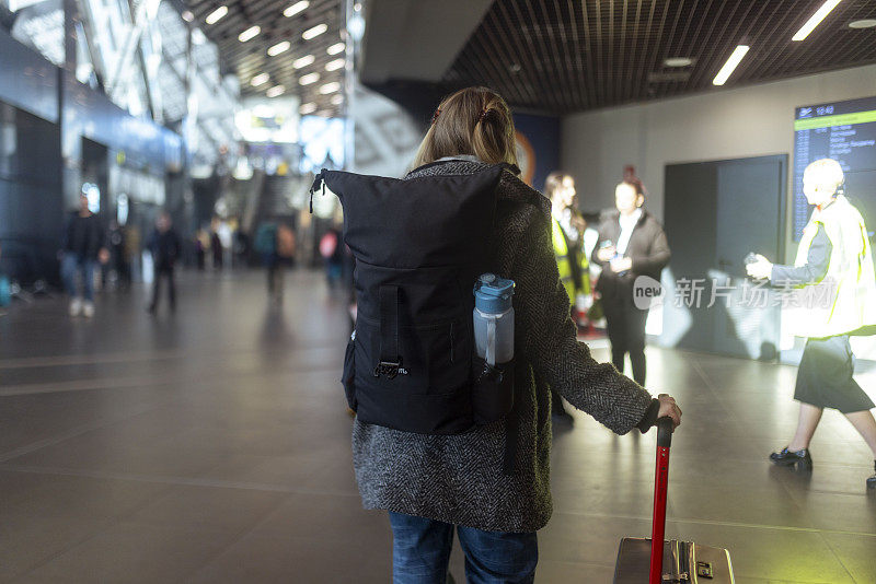 一位女游客正在机场候机，在登机牌上查询航班起飞时间