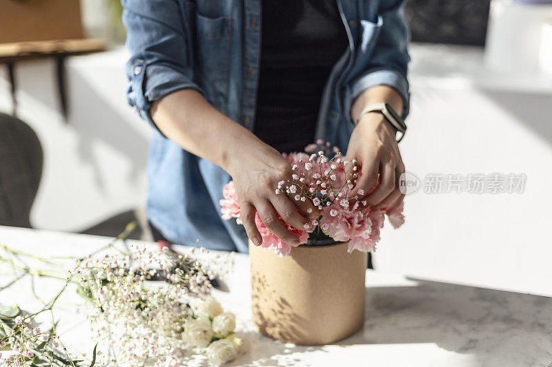 年轻漂亮的花匠在花店制作花束