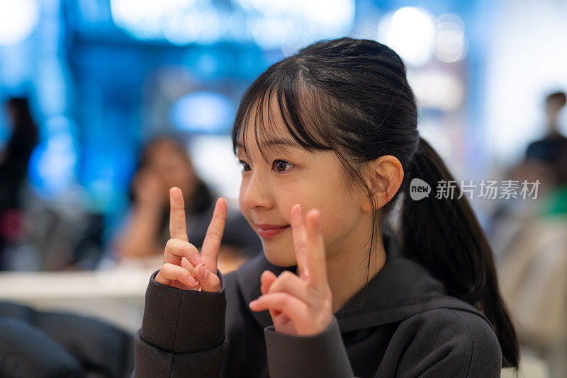 一个十几岁的女孩在咖啡馆里向她妈妈做了一个和平的手势