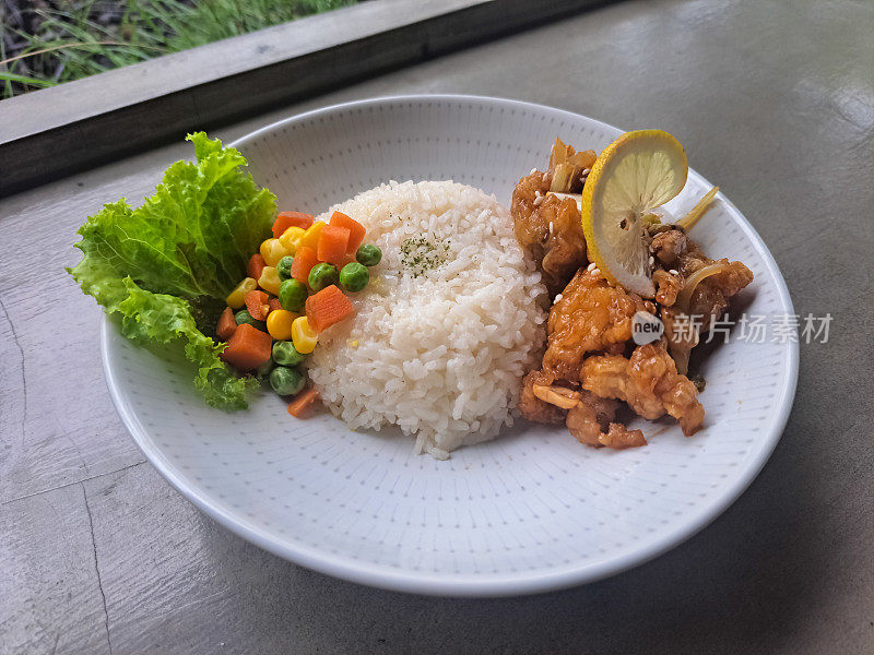 鸡宫保用鸡肉，米饭，生菜，青柠片，花生和混合蔬菜。食品菜单。