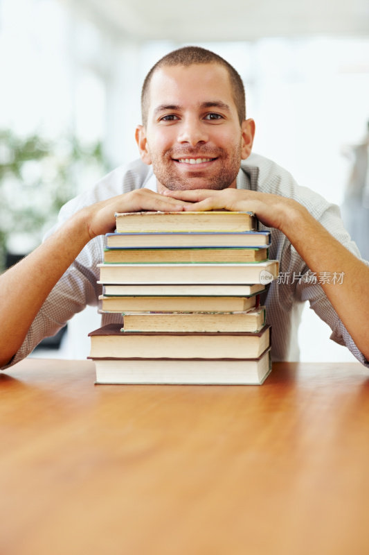微笑的年轻学生与一堆书
