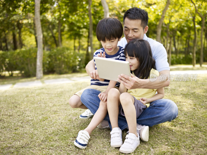 亚洲父亲和孩子在户外使用平板电脑