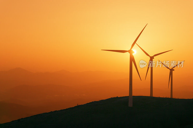 风力涡轮机的剪影在日落的山上