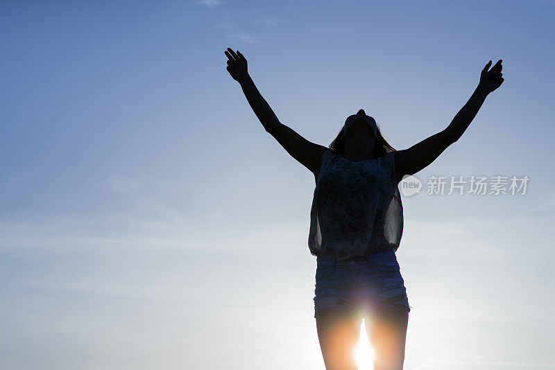 欢呼的女人在阳光下张开双臂