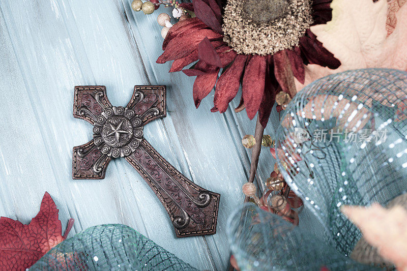 十字架上有蓝色，棕色的丝带，花和叶。