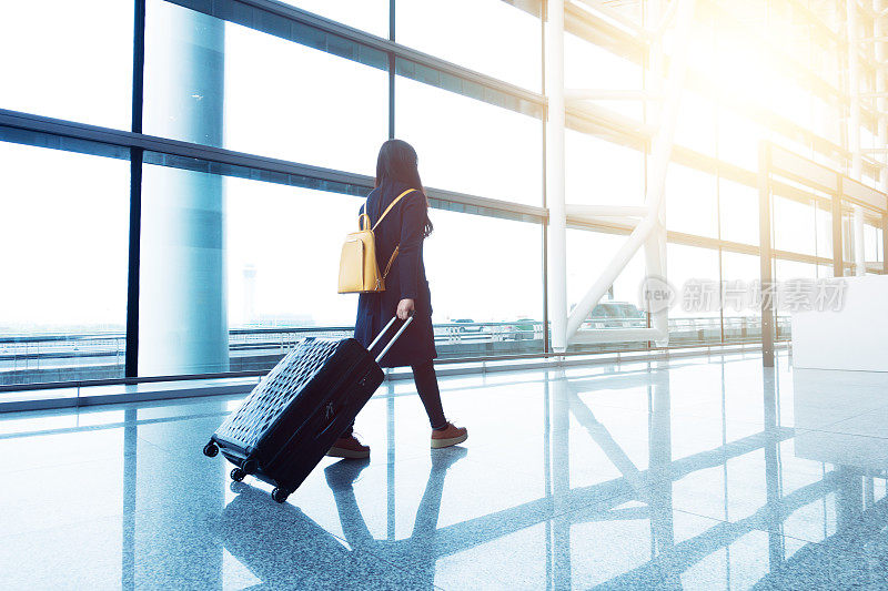 一个年轻女子带着行李在机场走来走去。