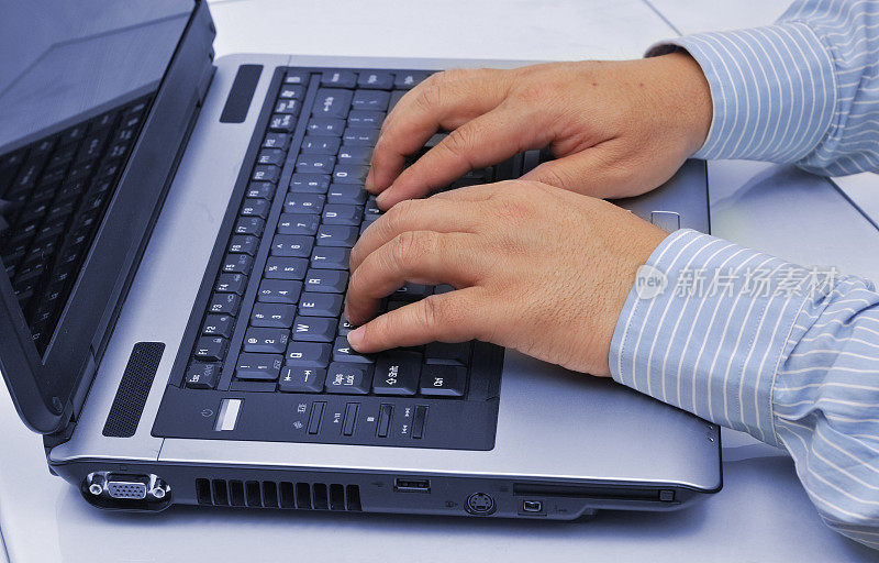 男人的手放在笔记本电脑的键盘上