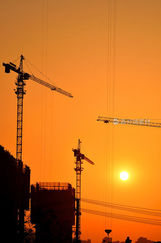 夕阳下的工地起重机和建筑