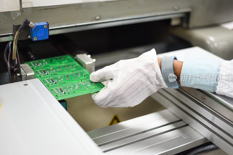 电子制造工厂工人用防静电齿轮手动从SMT生产线上拆卸印刷电路板