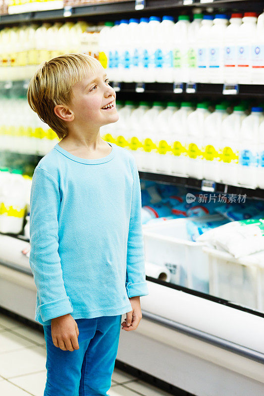 可爱，微笑的金发小女孩在超市的乳制品冰箱