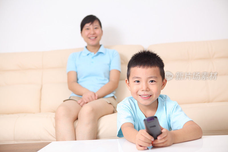 微笑的母亲和儿子在看电视