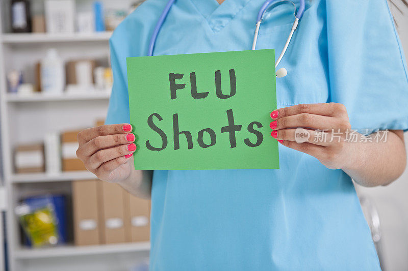 护士在诊所或药房拿着“流感疫苗”的牌子。