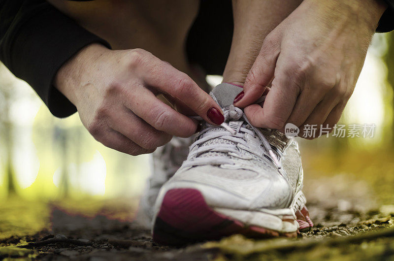 晨曦中，在森林里系运动鞋的女人