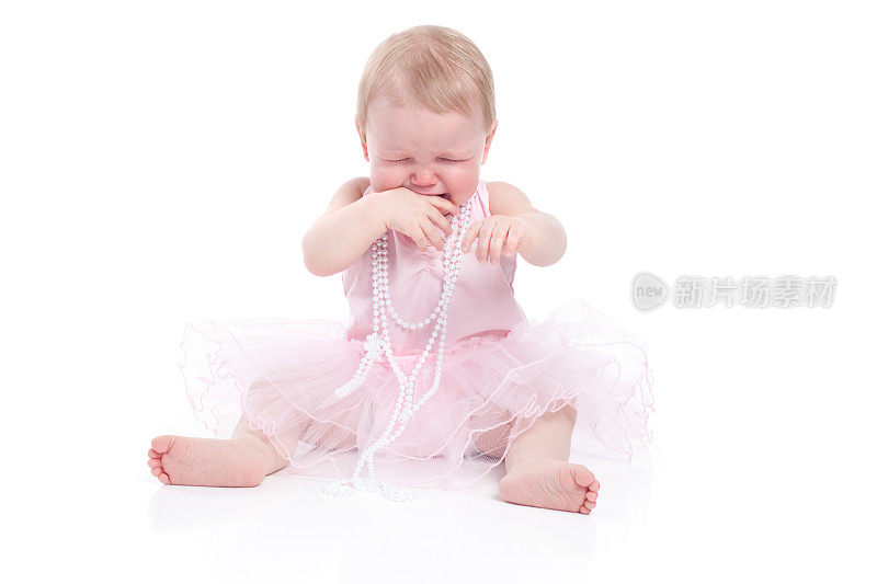 哭泣的婴儿穿着粉红色的芭蕾舞裙和珍珠