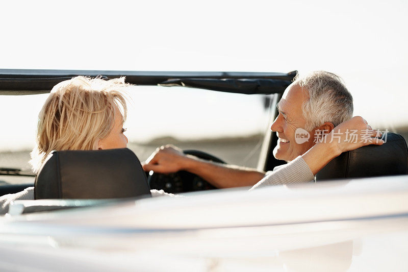 一对老年夫妇微笑着开车去度假