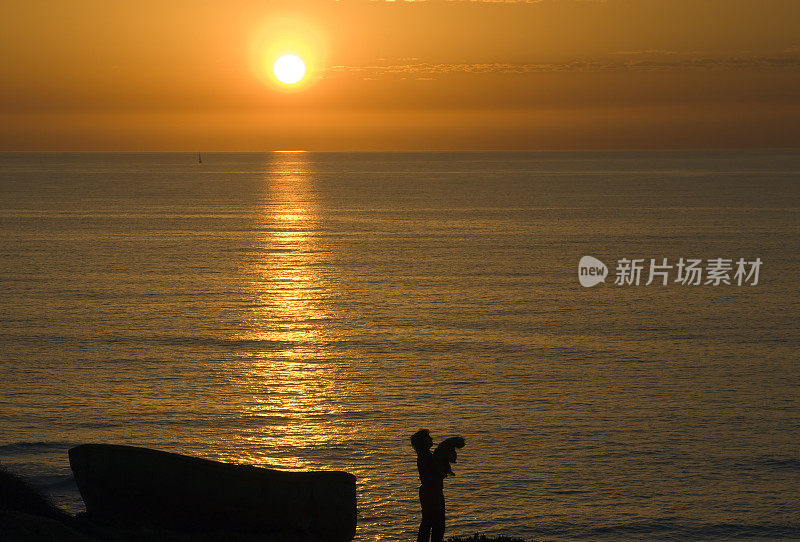 日落时的女人、狗和船