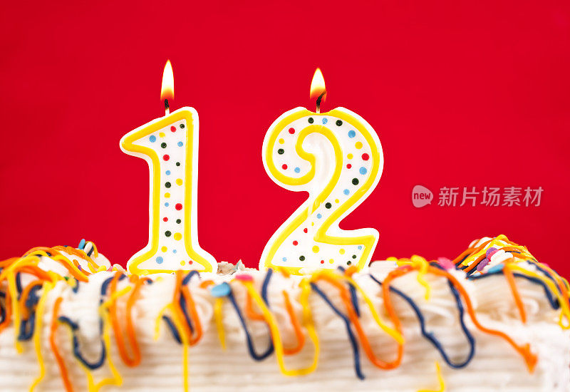 用12号燃烧的蜡烛装饰生日蛋糕。红色的背景。