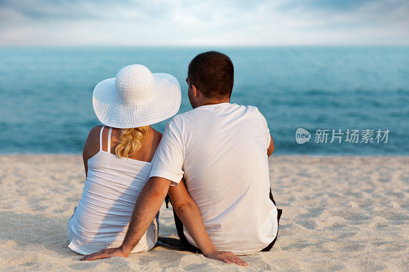 后视图的年轻夫妇放松在热带海滩