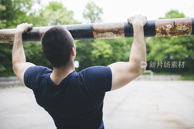 一个年轻人在户外单杠上做引体向上