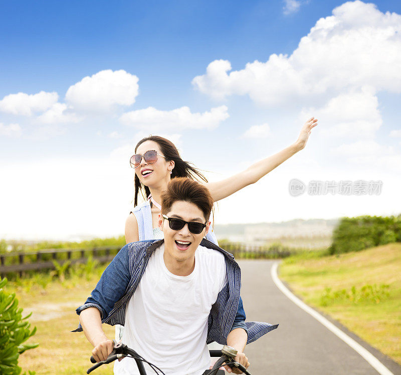 快乐的年轻夫妇在公园里骑自行车