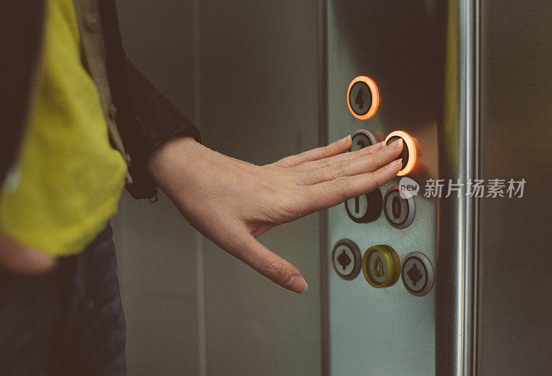 女人在电梯里按按钮。