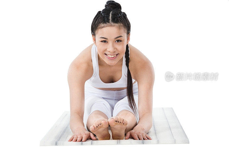微笑的亚洲女孩在运动服装练习向前弯曲的姿势瑜伽垫上孤立的白色