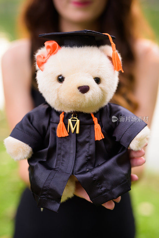 年轻女子送泰迪熊的肖像，泰迪熊上有毕业礼服和学位帽