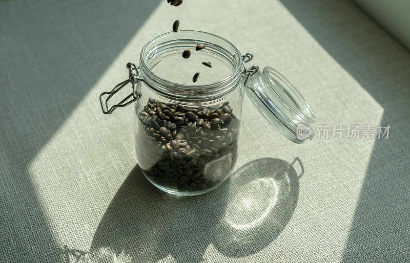 在阳光下将咖啡豆倒入玻璃瓶