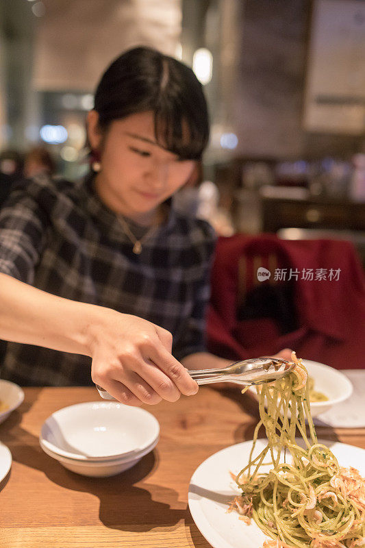 在餐厅做意大利面的年轻女子