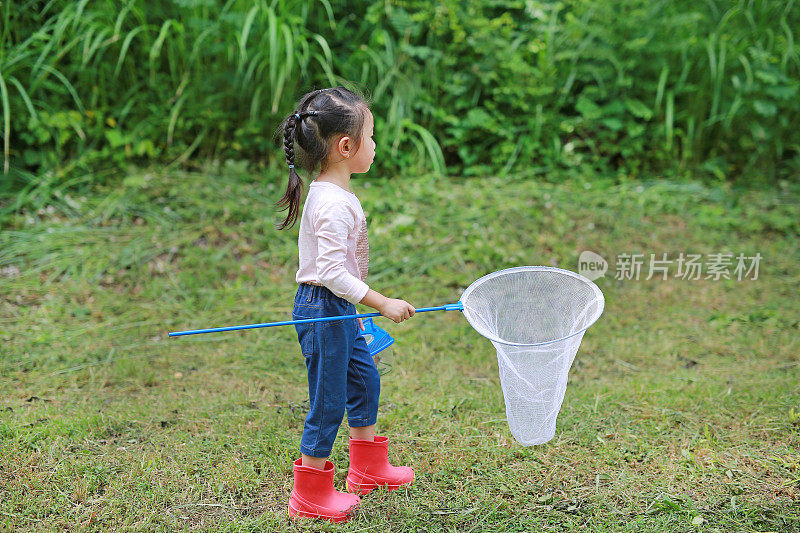 可爱的亚洲小女孩戴着草帽，在田野里戴着蚊帐。