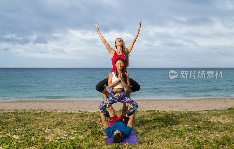 3人杂技瑜伽姿势在海边