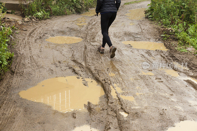 一个女人走在泥泞的路上。