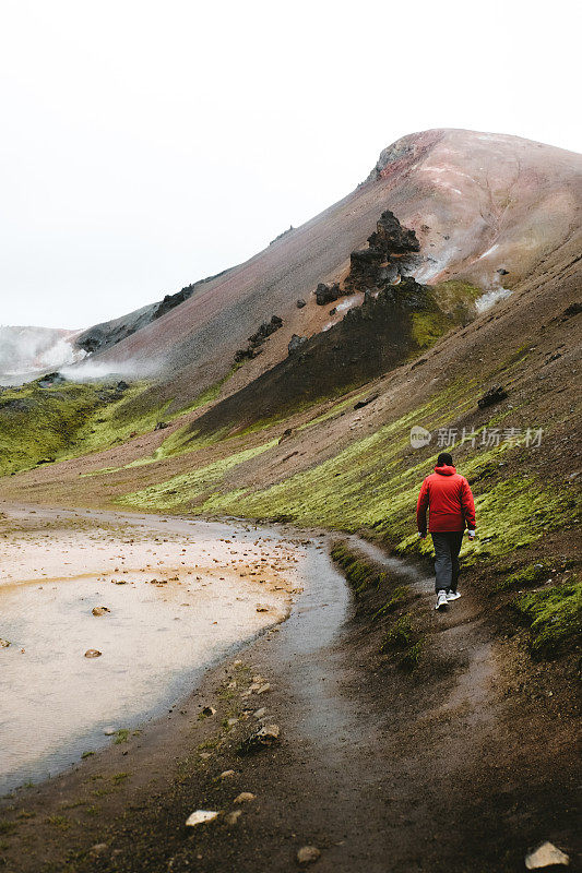 红色的男人在冰岛高地的地热地区徒步旅行