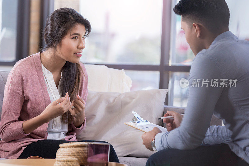 一位年轻女子坐在她的治疗师对面，用手势表达自己的想法