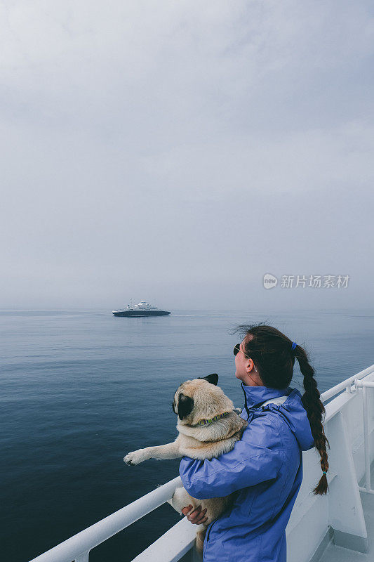 在挪威渡海时，女人和狗看着大海