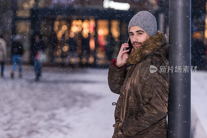 在一个下雪天，一个年轻人在参观城市购物中心后打电话。