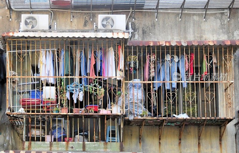 窗上挂满衣服的铁笼和破旧的公寓楼-中国澳门