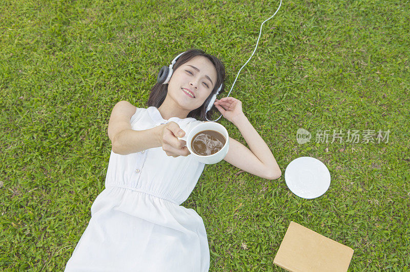 漂亮女人躺在草地上听音乐
