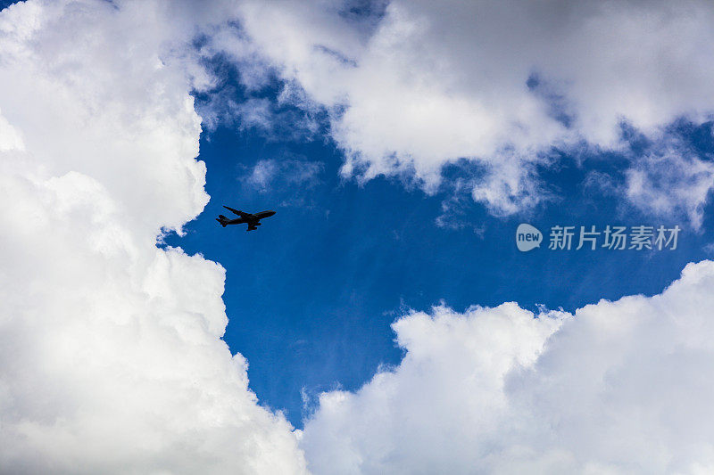 一架商业飞机飞过湛蓝的天空和白云。