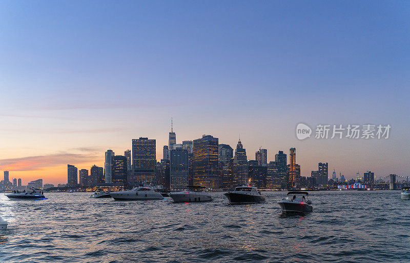 日落时分，曼哈顿市中心前的东河上有许多游艇。