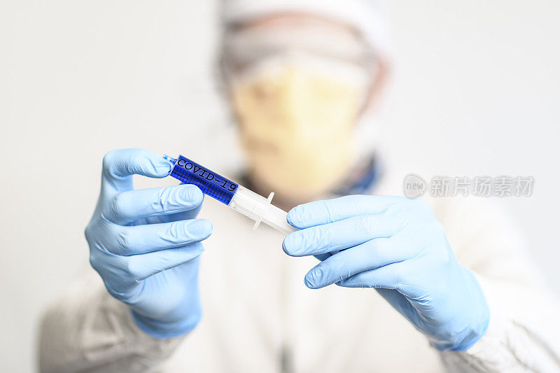 医生持有注射器和穿戴防护医疗设备，以防止传播冠状病毒
