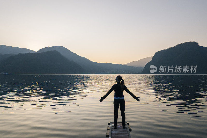 在码头的尽头，一名女子在湖上迎接日出