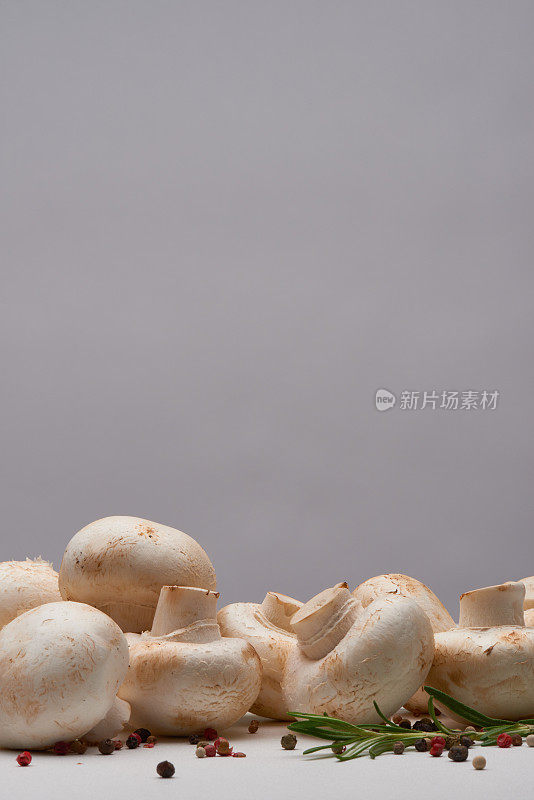 背景图片的原料，如白钮扣蘑菇，胡椒和迷迭香在干净的桌子上